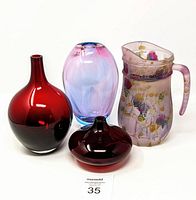 Four colored glass pieces including three red/lavender vases and one frosted glass pitcher with floral watercolor design.
