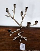 Full view of the silver metal candle holder shaped like a branch with seven candle cups.