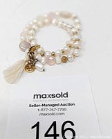 Double wrap pearl bracelet with gold bead spacers and detachable tassel charm shown coiled