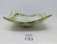Side view of green glass dish with gold flecks showing shape and color