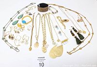 Full spread of gold plated costume jewelry pieces including necklaces, bracelets, rings, and earrings arranged on a white surface.