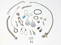 Full view of all costume jewelry pieces laid out, showing variety of necklaces, earrings, bracelets, rings, and pendants in silver plated metal.