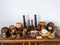 Lot of vintage wooden decorative bowls, candlesticks, holders, carved dolphins on driftwood, globe bookends, and other wooden decor items arranged on a wooden surface.