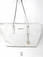 Front view of white Michael Kors Jet Set Travel tote bag with long handles and gold-tone MK charm.