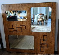 Front face of the vanity mirror showing the wood frame with three inset rectangular mirrors in different sizes and geometric black line patterns on the wood.