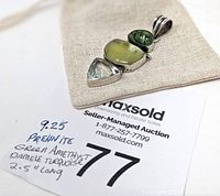 Photo of the full pendant placed on a fabric pouch next to a MaxSold lot card showing handwritten details: 925 , Prehnite, Green Amethyst, Damale Turquoise, 2.5" long.