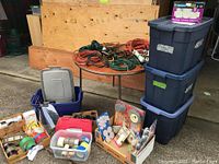 Wide view of table with three large bins and various items arranged including light bulbs, tapes, small parts, wireless puck lights and boxes