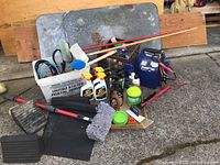 Photo showing grouped automotive supplies including air compressor/battery charger, jumper cables, cleaning brushes, spray bottles, and rubber pads and blocks.