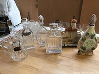 Full view of vintage liquor bottles and decanters including crystal and ceramic bottles with wide bottom Baccarat decanter visible.