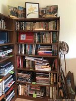 Full bookshelf showing six shelves of books plus top shelf prints and books