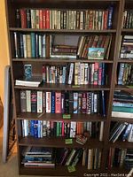 Six-shelf wooden bookcase filled with various WWII-themed books on three lower shelves