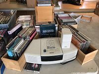 Overview of Bose player, speaker, and CDs arranged in wooden boxes on table