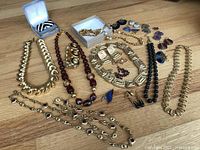 Full display of jewelry items on wooden surface showing necklaces, earrings, and other pieces.