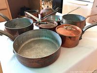 Overview of entire collection showing skillet, pots, kettle and lids arranged on table