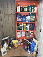 Photo of orange shelf filled with garden enhancer and inhibiting products including Ortho insecticides and fertilizers along with some bags of fertilizer on the floor.