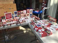 Wide view of multiple Hallmark Keepsake ornament boxes of various sizes arranged on two tables in a garage or workshop setting.