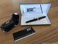 Overview of open presentation case holding fountain pen, ink bottle, and guarantee pamphlet