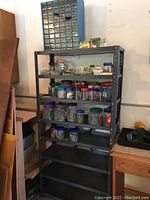 60-drawer blue plastic organizer filled with small hardware and metal rack with 8 shelves holding multiple jars of nails and screws.