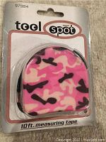 Photo of unopened Tool Spot 10 foot measuring tape with pink camouflage design on packaging