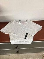 White lace short sleeve top displayed flat to show fabric and design details