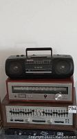 Panasonic boombox cassette player atop vintage audio receiver and equalizer