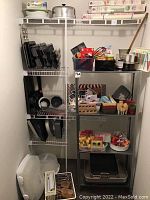 Wide view of basement storage with baking pans and metal shelving unit loaded with baking items.