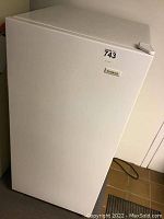 Front view of the white Beaumark standing freezer showing the door closed and a lot sticker on the upper corner.