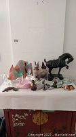 Full view of assorted animal figurines and sculptures laid out on a white table, showing variety in materials, colors, and animal types