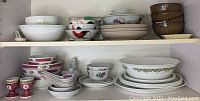 Two shelves of assorted dishes including bowls, salad plates, small and medium saucers, and egg cups with Chinese patterns