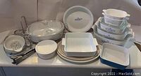 Photo showing entire Corningware and Pyrex set on a table with wire stand and metal tongs.