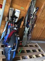 Photo showing golf bags, golf clubs and ski bags with poles grouped together in storage area.
