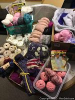 Overview of yarn skeins, knitting patterns, and some needles arranged in baskets and containers showing color variety and textures