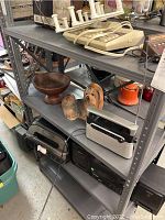 Shelf with beige landline telephone, wooden bowl, ceramic dog figurine, and radios including black and silver models.