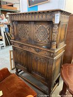 Front view of carved wooden sideboard showing floral carvings and locked cabinet.