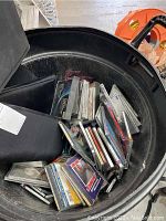 View of multiple CDs in a large black plastic container, showing cases stacked with some visible titles.