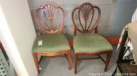 Pair of wooden dining chairs side by side showing back design and padded seats.