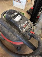 Red and black Craftsman wet/dry vacuum cleaner with attached hose, showing brand and power label.