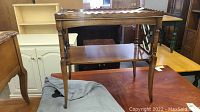 Wooden end table on display showing front and side with tray top and shelf