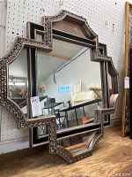Full view of the decorative framed mirror leaning against pegboard.