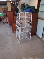 Single white wire drawer unit upright with three wire mesh drawers, in warehouse setting.