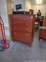 Front view of the tall dresser showing all five drawers with brushed nickel knobs and smooth cherry finish.