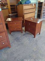 Photo showing both nightstands side by side, each with two drawers and metal knobs, reddish-brown wood finish, slight inward curve at base.