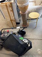 Photo of Craftsman gas-powered lawnmower showing side view with attached grass collection bag and visible wear on wheels and engine area.