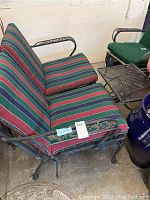 Photo of the two-seat metal patio loveseat with striped green, red, and blue cushions, showing furniture frame and cushion condition.