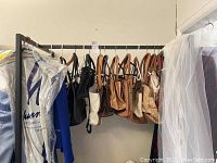 Side view of purses hanging on the rack, assorted in colors like black, brown, and beige.