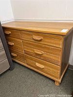 Front and side perspective of worn oak dresser showing drawer fronts and wooden handles.