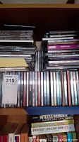 View of CD collection in jewel cases stacked tightly with varied artists visible, showing at least two layers deep.
