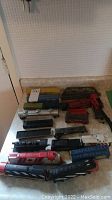 Full overview of the model train components arranged on a countertop including locomotives, cars, and a bridge