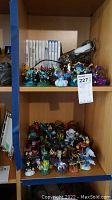 Shelf with Wii and Wii U game cases and Skylanders figurines including characters in various colors and poses.