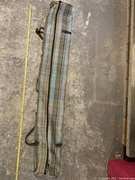 Full length of the DAKINE travel ski bag laid on the floor, showing plaid pattern and zipper running the full length.